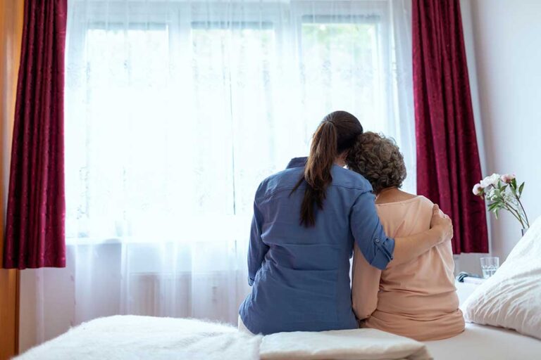 Older adult and family member reviewing care options with a nurse at a dining table.